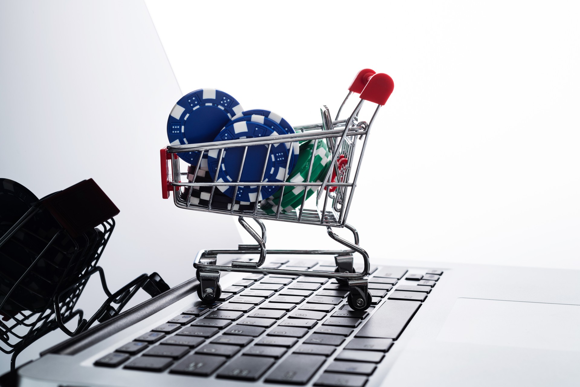 Shopping cart with gambling chips on laptop keyboard